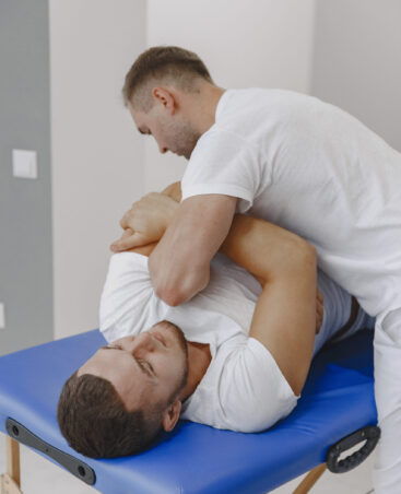 Man in the medical office. Physiotherapist is rehabilitating back.